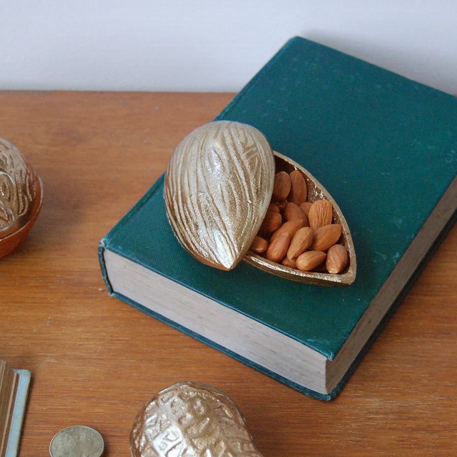 Decorative gold almond dish used for small storage in styled vignette