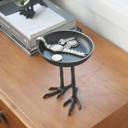 Sculptural black trinket dish with tall bird legs styled indoors