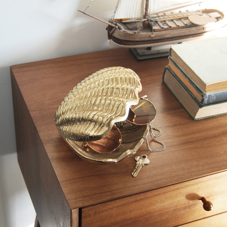 Gold clam ornament with open shell interior shown in a coastal-inspired setting