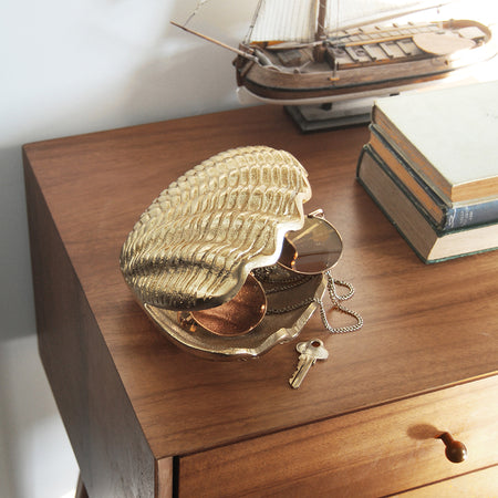 Gold clam ornament with open shell interior shown in a coastal-inspired setting