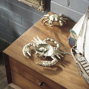 Decorative gold crab trinket dish styled beside books and nautical décor
