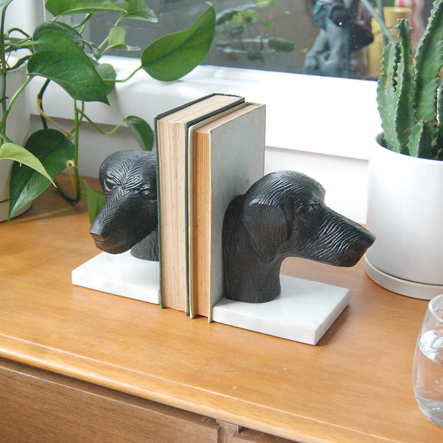 Black dog head bookends holding vintage books on marble bases