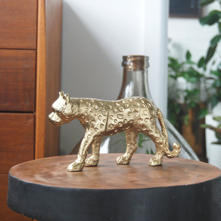 Decorative gold leopard statue on timber surface