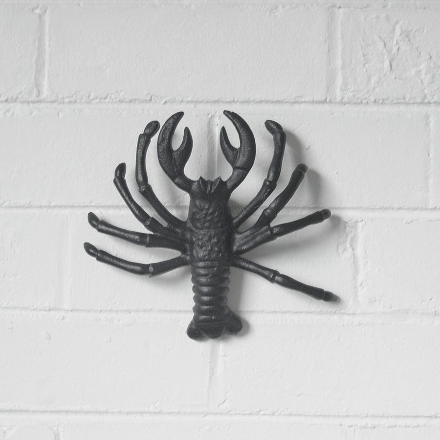 Sculptural matte black lobster mounted on interior wall