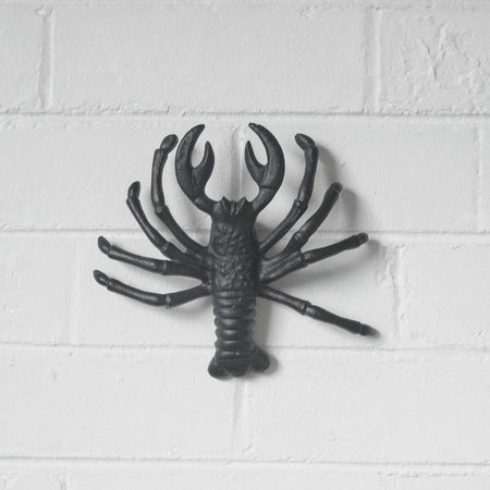 Sculptural matte black lobster mounted on interior wall