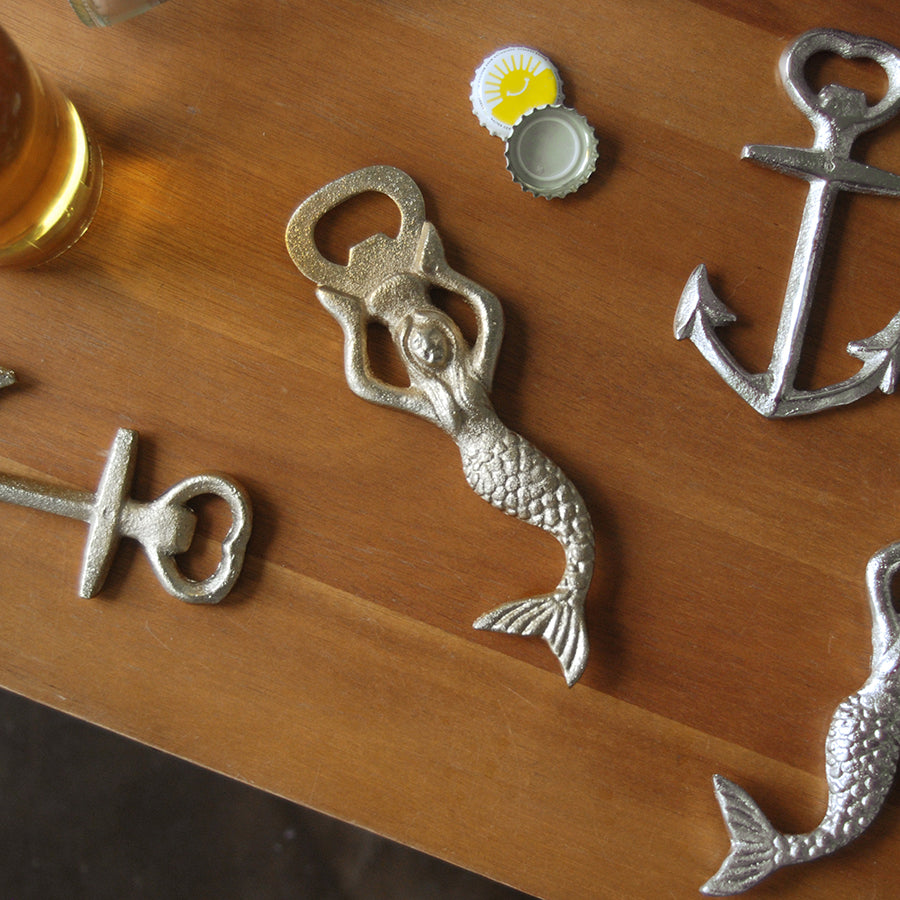 Metallic mermaid-shaped bottle opener styled with drinks