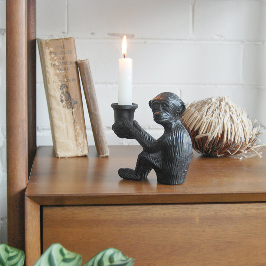 Decorative matte black monkey sculpture holding candle