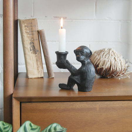 Decorative matte black monkey sculpture holding candle