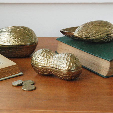 Sculptural gold peanut container surrounded by books and coins