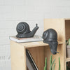 Whimsical matte black snail by White Moose used in playful home decor setup on timber furniture 
