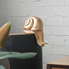 Gold resin snail sculpture perched on the edge of a black and timber console