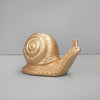 Shiny gold snail decor piece with spiral shell styled in a minimalist living space