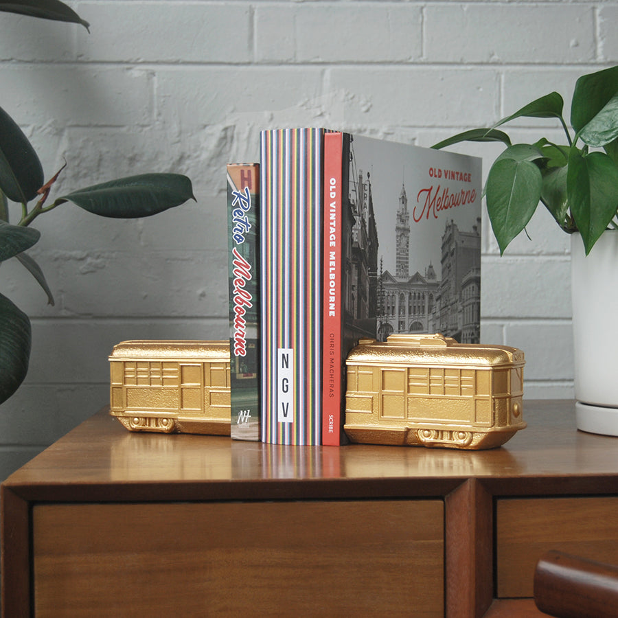 Gold resin Melbourne tram bookends styled with vintage Melbourne books on timber cabinet