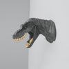 Matte black T-Rex wall sculpture with gold teeth mounted on a white wall