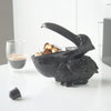 Matte black pelican sculpture used to hold coffee pods on a white bench