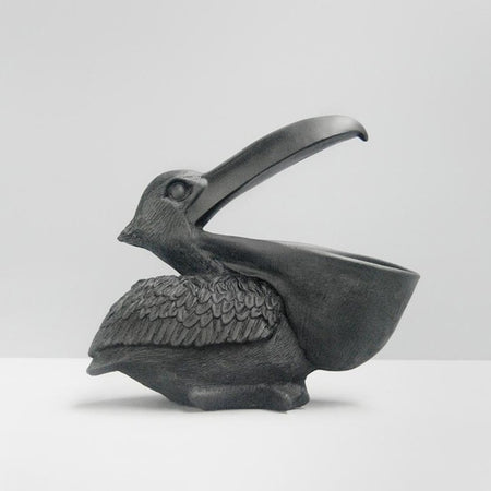 Black pelican sculpture with open beak storage used as functional decor