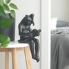 Resin monkey sculpture reading book on white table
