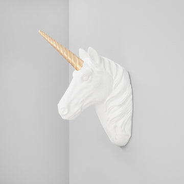 Unicorn wall sculpture in matte white resin with gold horn mounted on a grey wall